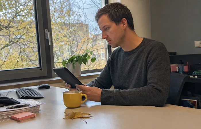 Iemand leest een Beeldbank-update op een tablet in herfstsfeer
