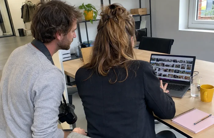 Fotograaf en communicatiemedewerker bekijken samen een fotobibliotheek